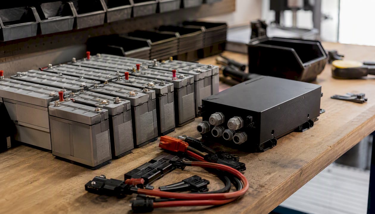 Auf der Werkbank liegen verschiedene Bauteile eines modularen PV-Batteriesystems bereit.